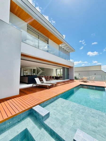 Fachada da casa com piscina e deck de madeira